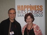 photo of David Van Nuys, Ph.D. and Beth Phelan in front of Happiness Conference sign